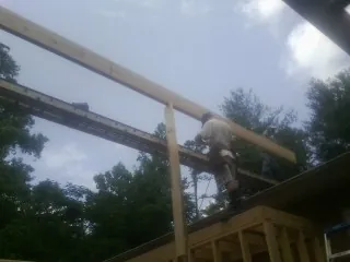 Carpenter setting a ridge beam over a new addition frame — Ice Dam Removal by Roofing Brothers in Falmouth