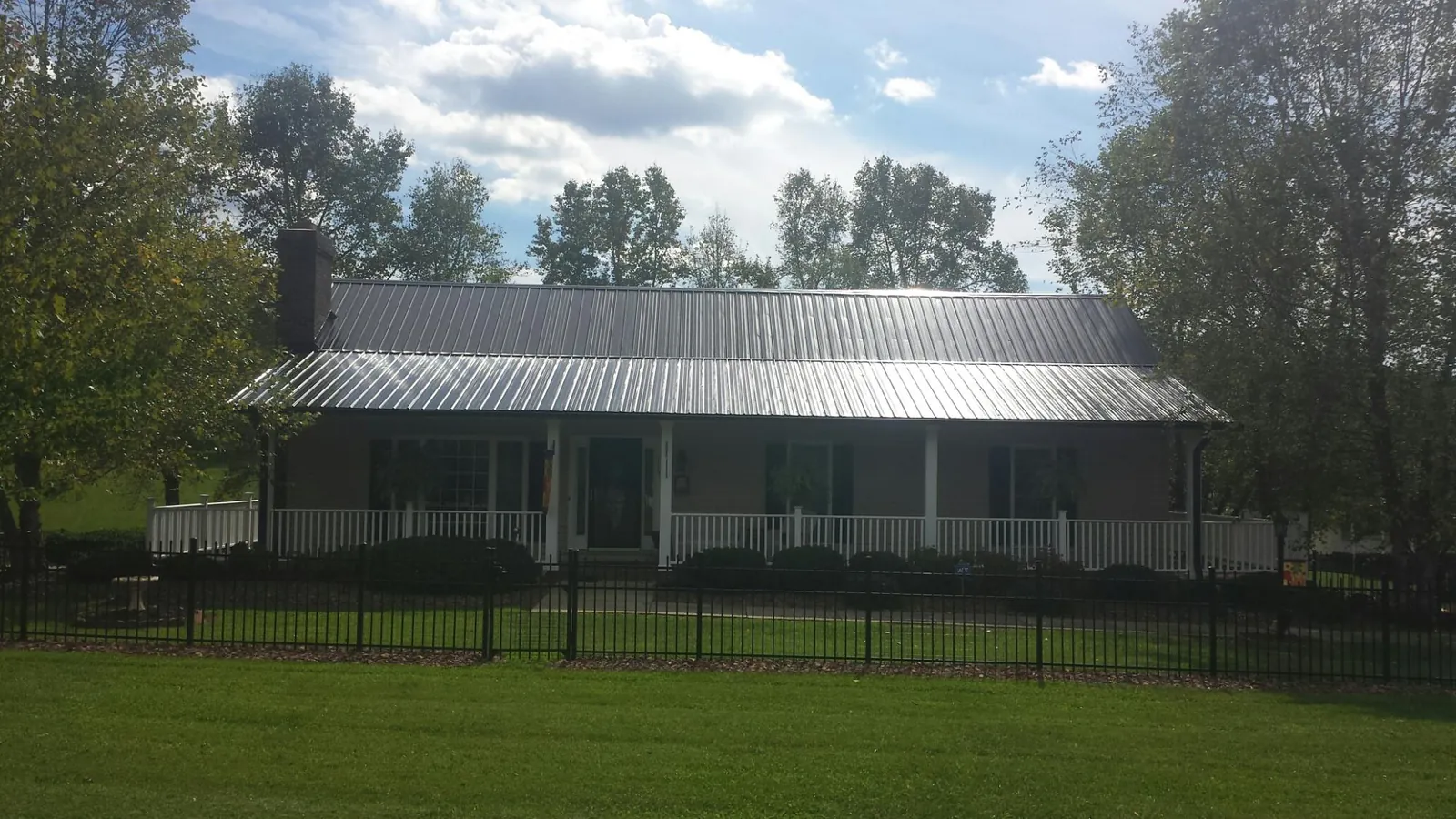 Gray metal roof on a brick ranch with a full width front porch — Gutter Guard Installation work by our crew in Falmouth